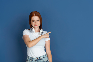 Image showing Caucasian young girl\'s portrait isolated on blue studio background. Beautiful female model. Concept of human emotions, facial expression, sales, ad, youth culture.