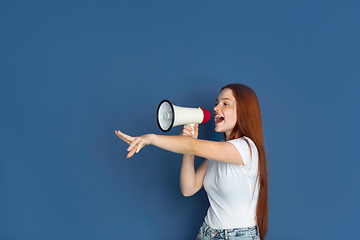 Image showing Caucasian young girl\'s portrait isolated on blue studio background. Beautiful female model. Concept of human emotions, facial expression, sales, ad, youth culture.