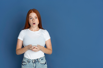 Image showing Caucasian young girl\'s portrait isolated on blue studio background. Beautiful female model. Concept of human emotions, facial expression, sales, ad, youth culture.