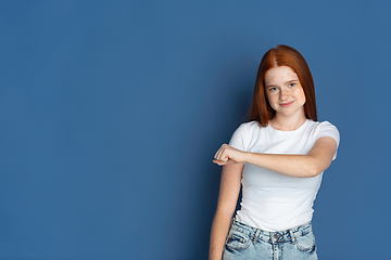 Image showing Caucasian young girl\'s portrait isolated on blue studio background. Beautiful female model. Concept of human emotions, facial expression, sales, ad, youth culture.