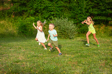 Image showing Kids, children running on meadow in summer\'s sunlight