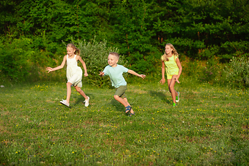 Image showing Kids, children running on meadow in summer\'s sunlight