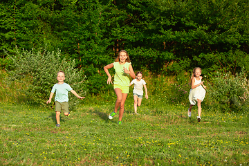 Image showing Kids, children running on meadow in summer\'s sunlight