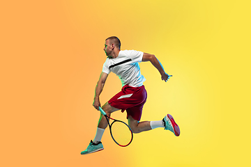 Image showing Caucasian male professional sportsman playing tennis on studio background in neon light