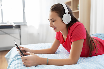 Image showing girl in headphones listening to music on tablet pc