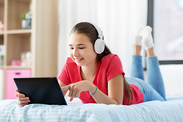 Image showing girl in headphones listening to music on tablet pc