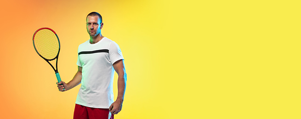 Image showing Caucasian male professional sportsman playing tennis on studio background in neon light