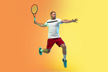 Image showing Caucasian male professional sportsman playing tennis on studio background in neon light