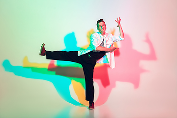 Image showing Young beautiful man dancing hip-hop, street style isolated on studio background in neon light