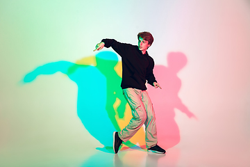 Image showing Young beautiful man dancing hip-hop, street style isolated on studio background in neon light