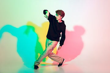 Image showing Young beautiful man dancing hip-hop, street style isolated on studio background in neon light