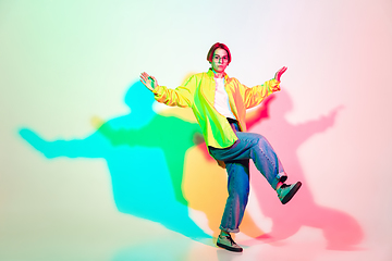 Image showing Young beautiful woman dancing hip-hop, street style isolated on studio background in neon light