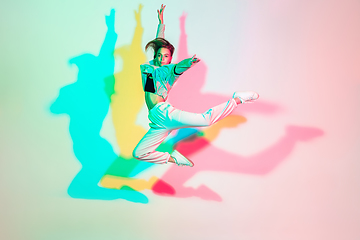 Image showing Young beautiful woman dancing hip-hop, street style isolated on studio background in neon light