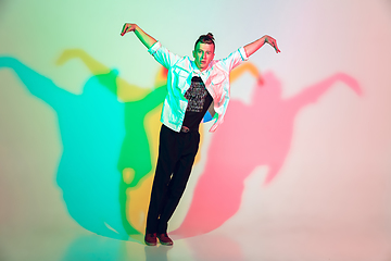 Image showing Young beautiful man dancing hip-hop, street style isolated on studio background in neon light