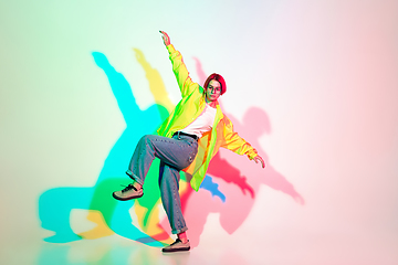 Image showing Young beautiful woman dancing hip-hop, street style isolated on studio background in neon light