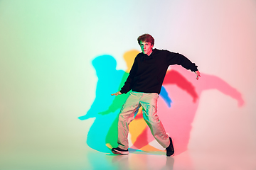 Image showing Young beautiful man dancing hip-hop, street style isolated on studio background in neon light