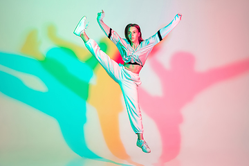 Image showing Young beautiful woman dancing hip-hop, street style isolated on studio background in neon light