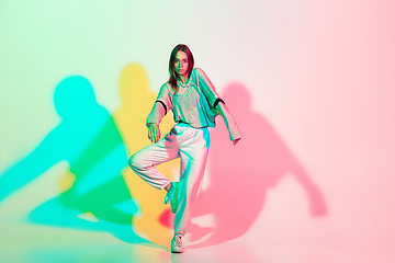 Image showing Young beautiful woman dancing hip-hop, street style isolated on studio background in neon light