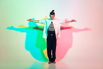 Image showing Young beautiful man dancing hip-hop, street style isolated on studio background in neon light