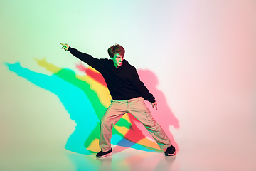 Image showing Young beautiful man dancing hip-hop, street style isolated on studio background in neon light