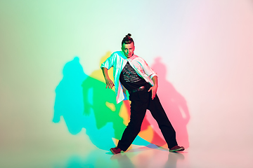 Image showing Young beautiful man dancing hip-hop, street style isolated on studio background in neon light