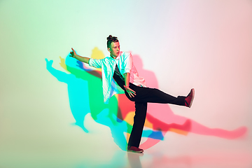 Image showing Young beautiful man dancing hip-hop, street style isolated on studio background in neon light