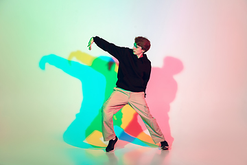 Image showing Young beautiful man dancing hip-hop, street style isolated on studio background in neon light