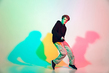 Image showing Young beautiful man dancing hip-hop, street style isolated on studio background in neon light