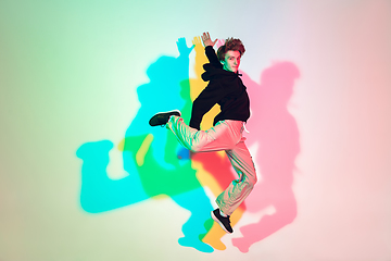 Image showing Young beautiful man dancing hip-hop, street style isolated on studio background in neon light