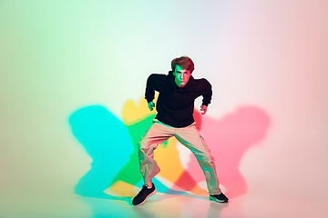 Image showing Young beautiful man dancing hip-hop, street style isolated on studio background in neon light