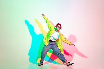 Image showing Young beautiful woman dancing hip-hop, street style isolated on studio background in neon light