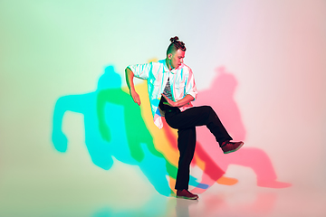 Image showing Young beautiful man dancing hip-hop, street style isolated on studio background in neon light