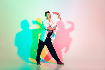 Image showing Young beautiful man dancing hip-hop, street style isolated on studio background in neon light