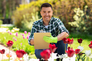 Image showing man with clipboard and flowers at summer garden