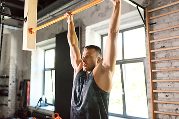 Image showing man exercising on bar and doing pull-ups in gym