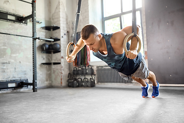 Image showing man doing push-ups on gymnastic rings in gym