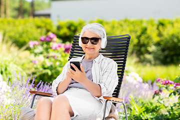 Image showing old woman with headphones and smartphone at garden