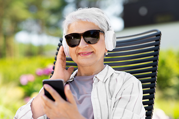 Image showing old woman with headphones and smartphone at garden