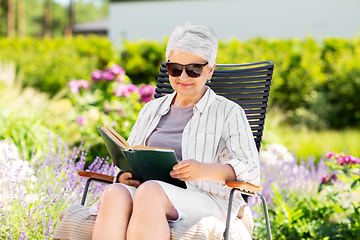 Image showing happy senior woman reading book at summer garden