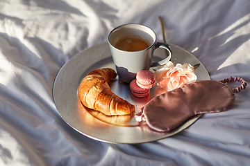 Image showing croissant, coffee and eye sleeping mask in bed