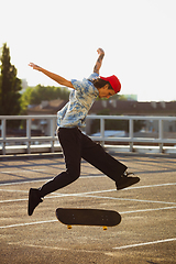 Image showing Skateboarder doing a trick at the city\'s street in summer\'s sunshine