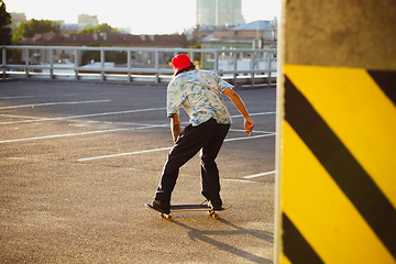 Image showing Skateboarder doing a trick at the city\'s street in summer\'s sunshine