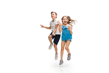 Image showing Happy little caucasian girl and boy jumping and running isolated on white background