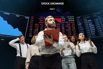 Image showing Nervous tensioned investors analyzing crisis stock market with charts on screen on background, falling stock exchange