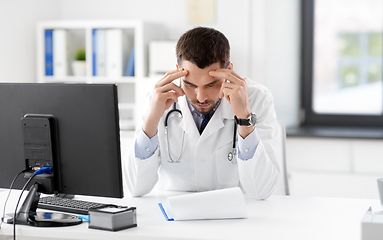 Image showing stressed male doctor with clipboard at hospital