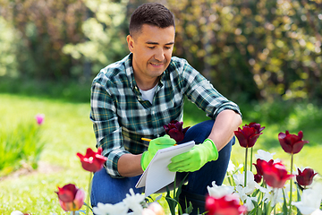 Image showing man with notebook and flowers at summer garden