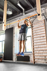 Image showing man exercising on bar and doing pull-ups in gym