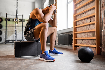 Image showing tired young man with medicine ball in gym