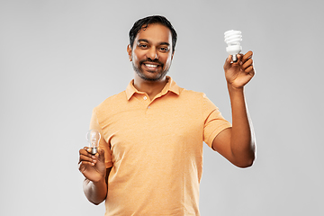 Image showing smiling indian man comparing different light bulbs