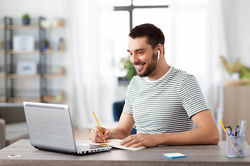 Image showing man with notebook, earphones and laptop at home